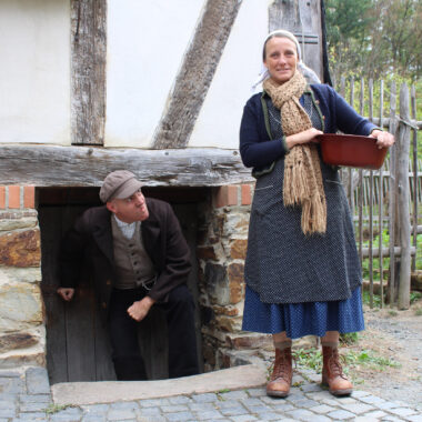 Zwei Schauspieler in historischen Kostümen stehen vor dem Haus aus Eisemroth.