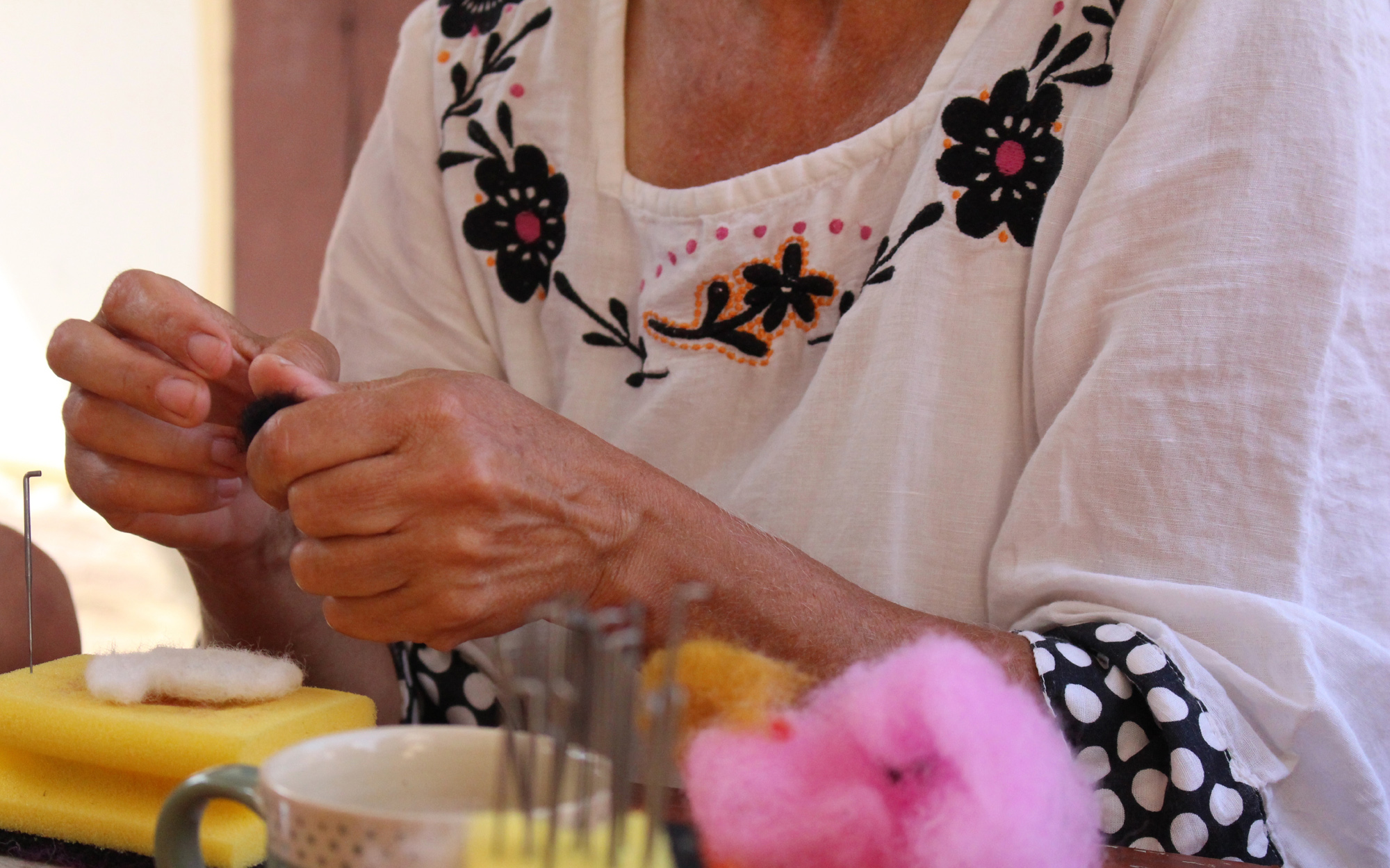 Eine Handwerkerin formt mit ihren Händen ein Stück Filz.