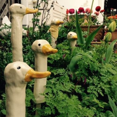 getöpferte Gänseköpfe in einem Blumenbeet